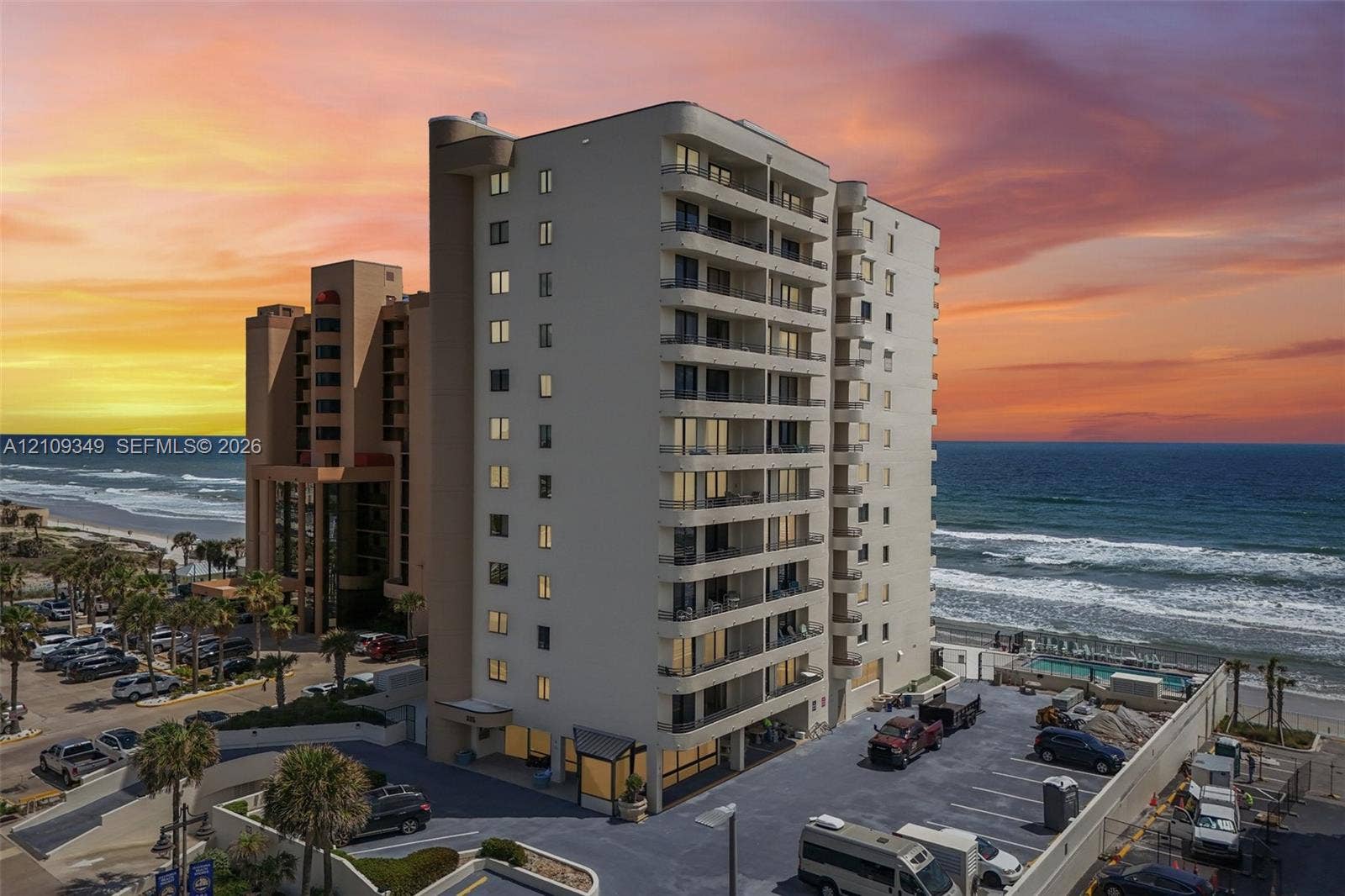 3115 S Atlantic Avenue, #G030, Daytona Beach, FL 32118 High-rise residential building featuring multiple private balconies, a concrete parking lot, and proximity to the coastline