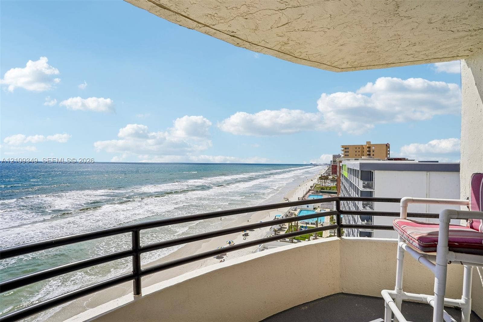 3115 S Atlantic Avenue, #G030, Daytona Beach, FL 32118 Covered balcony featuring concrete flooring, a solid concrete railing, and a black metal handrail with horizontal bars
