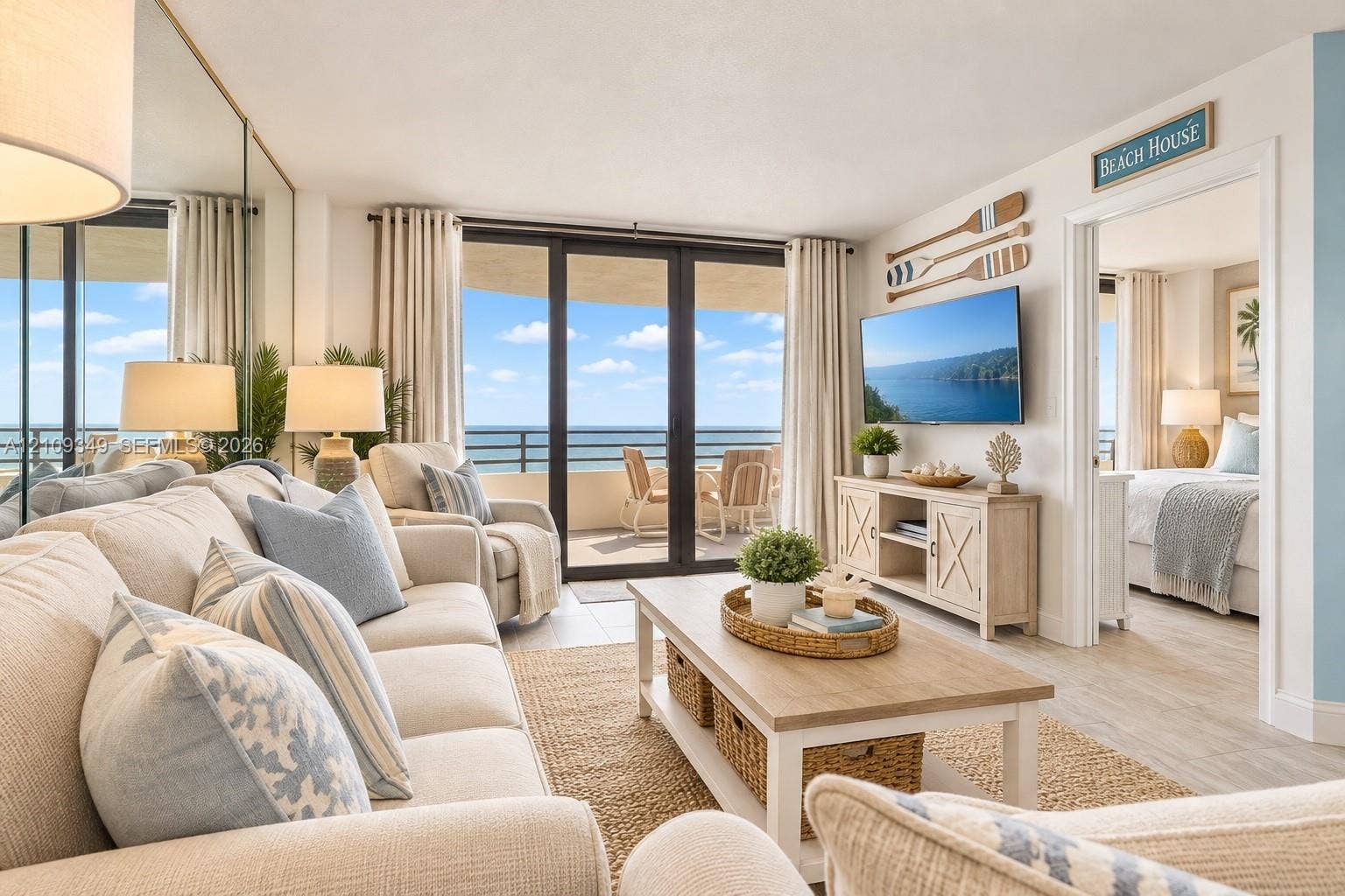 3115 S Atlantic Avenue, #G030, Daytona Beach, FL 32118 Living space featuring wood-finish flooring, floor-to-ceiling mirror paneling, and sliding glass doors opening to an exterior balcony