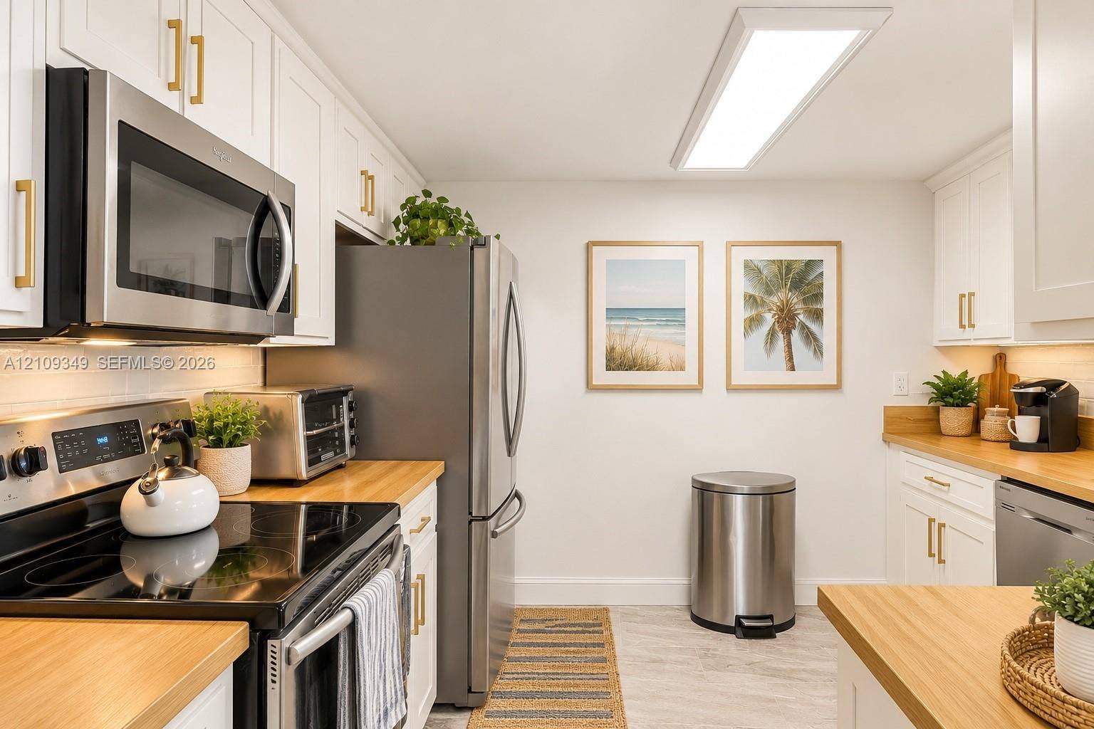 3115 S Atlantic Avenue, #G030, Daytona Beach, FL 32118 Kitchen featuring white shaker-style cabinetry, wood-finish countertops, stainless steel appliances, and integrated linear LED ceiling lighting