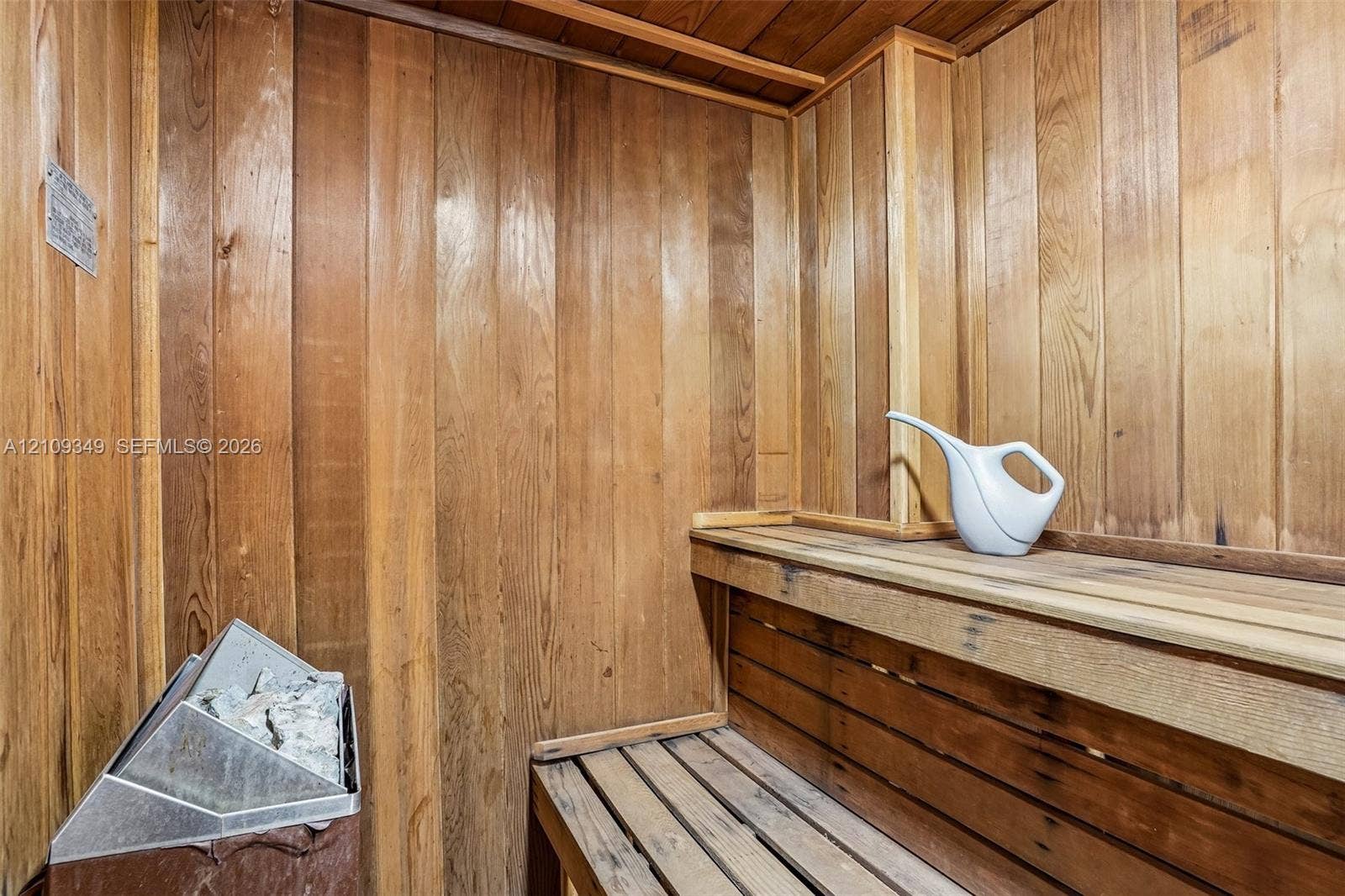 3115 S Atlantic Avenue, #G030, Daytona Beach, FL 32118 Sauna featuring tongue-and-groove wood wall paneling, multi-level wood bench seating, and a metal heating unit with stones