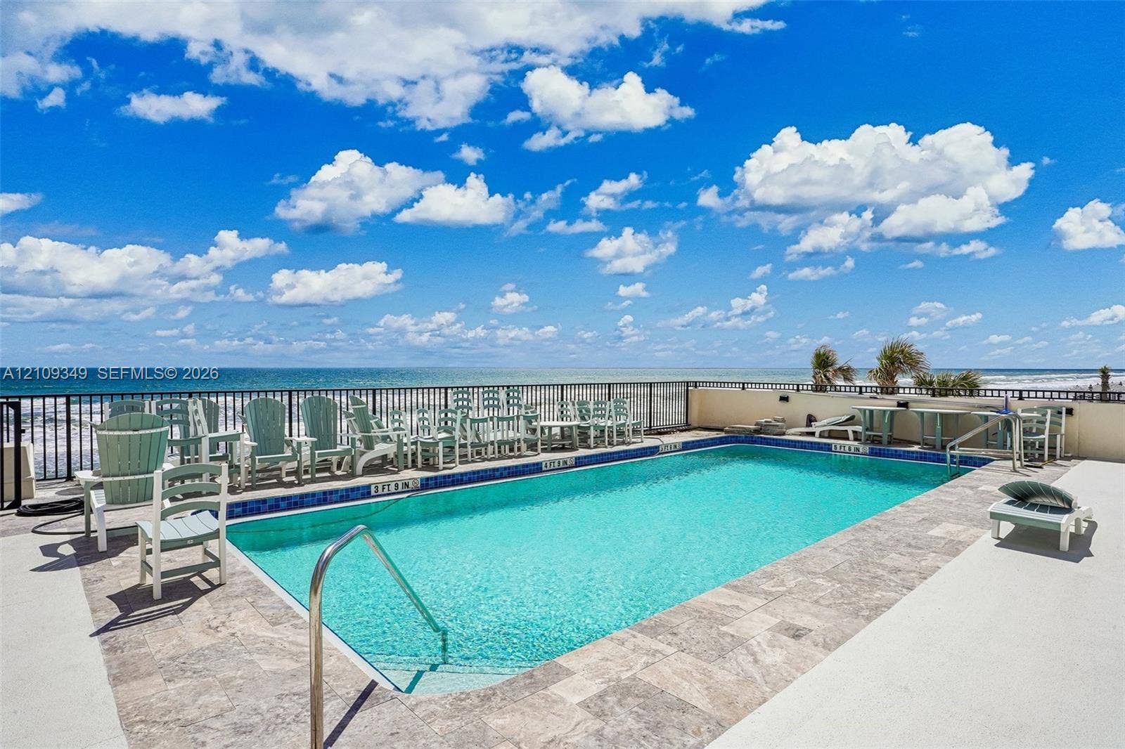 3115 S Atlantic Avenue, #G030, Daytona Beach, FL 32118 Swimming pool featuring stone-tile coping, metal perimeter fencing, and a metallic handrail