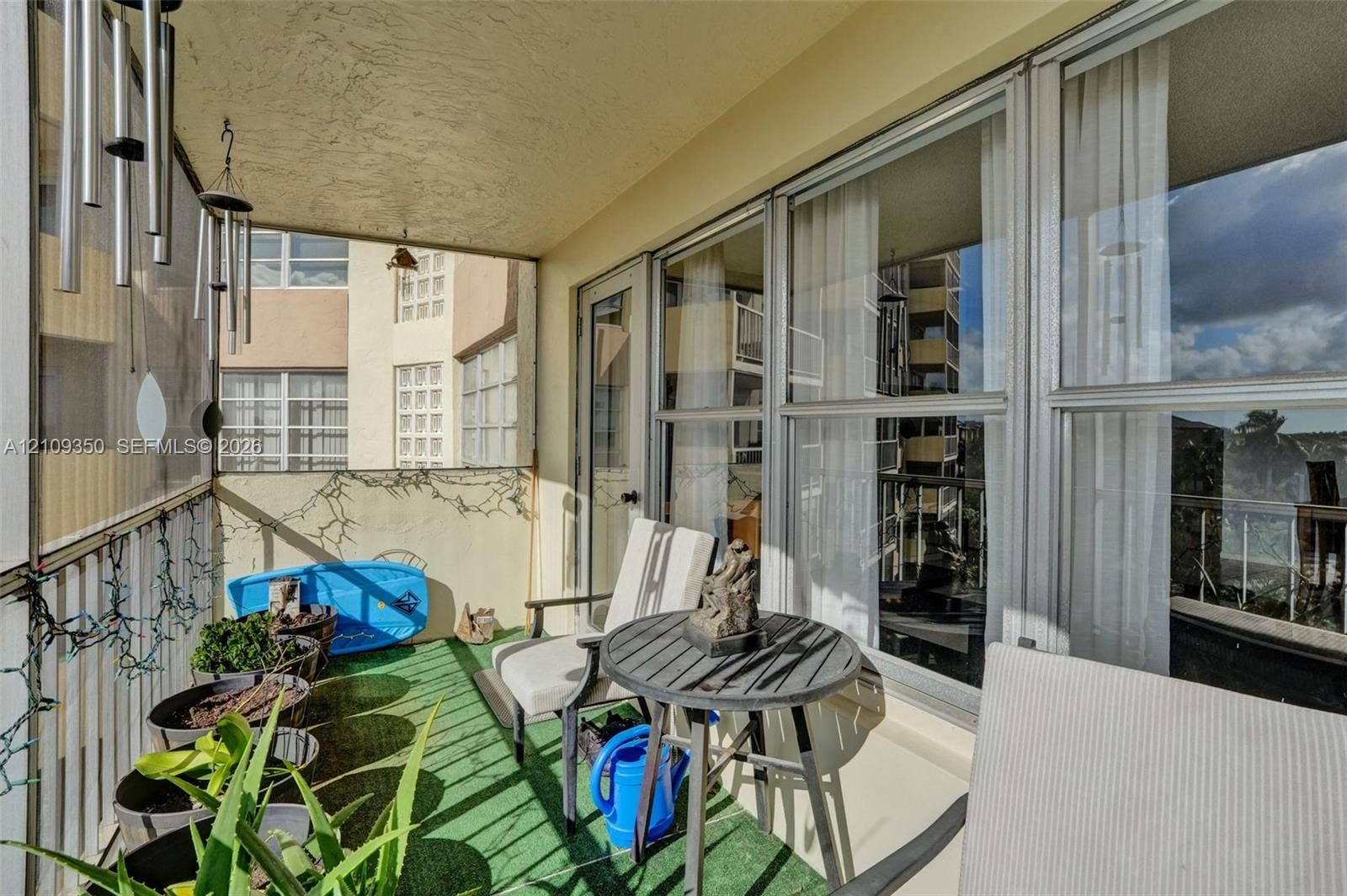 10777 W Sample Road, #616, Coral Springs, FL 33065 Covered balcony featuring metal railing, large floor-to-ceiling windows, and artificial turf flooring