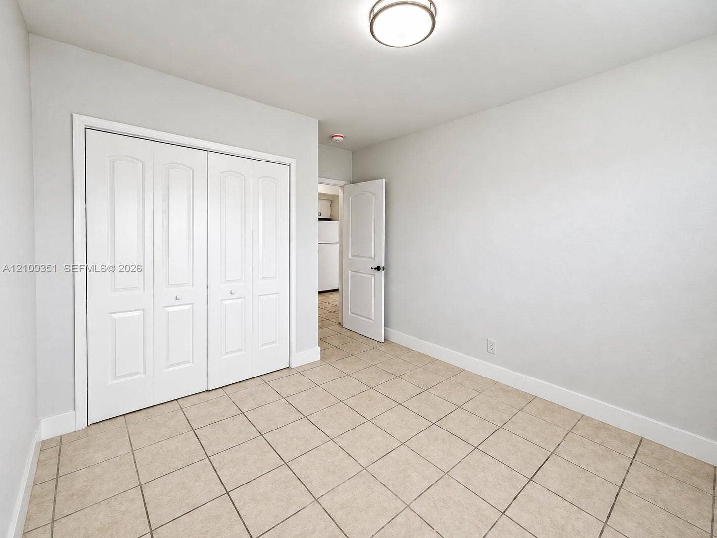 Interior room featuring neutral-toned tile flooring, recessed ceiling lighting, and a bi-fold door closet