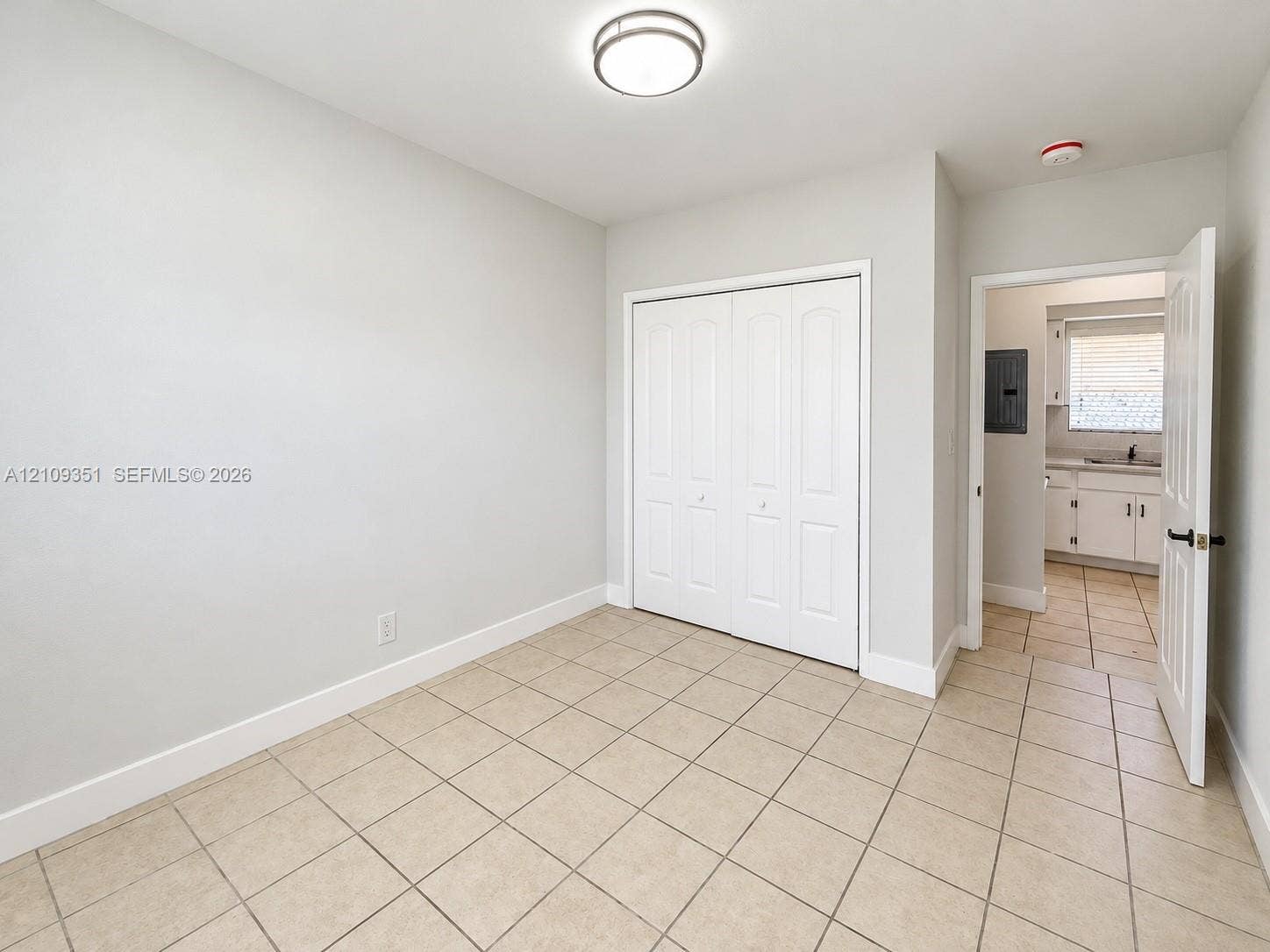Room featuring ceramic tile flooring, neutral wall paint, and a built-in closet with paneled double doors