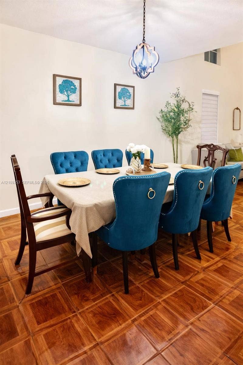 Dining area featuring parquet-patterned flooring, high ceilings, and a decorative pendant light fixture