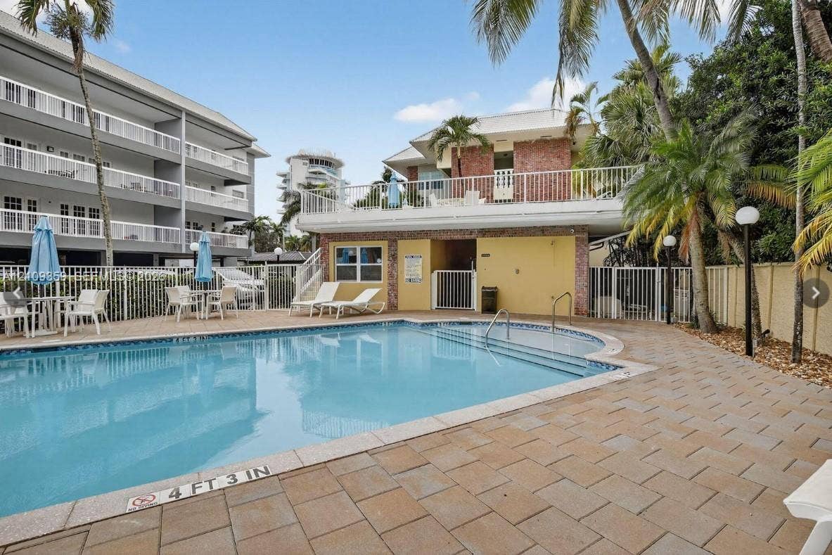 2426 SE 17th Causeway, #103A, Fort Lauderdale, FL 33316 In-ground pool with stepped entry and paver patio surrounded by metal perimeter fencing and mature palm trees