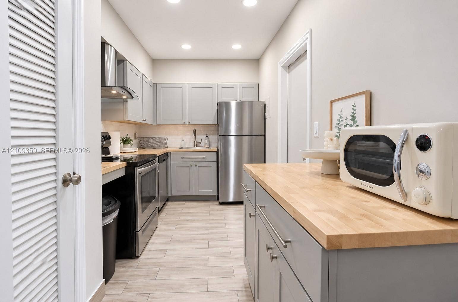 2426 SE 17th Causeway, #103A, Fort Lauderdale, FL 33316 Kitchen featuring grey cabinetry, wood-finish countertops, stainless steel appliances, and wood-finish tile flooring