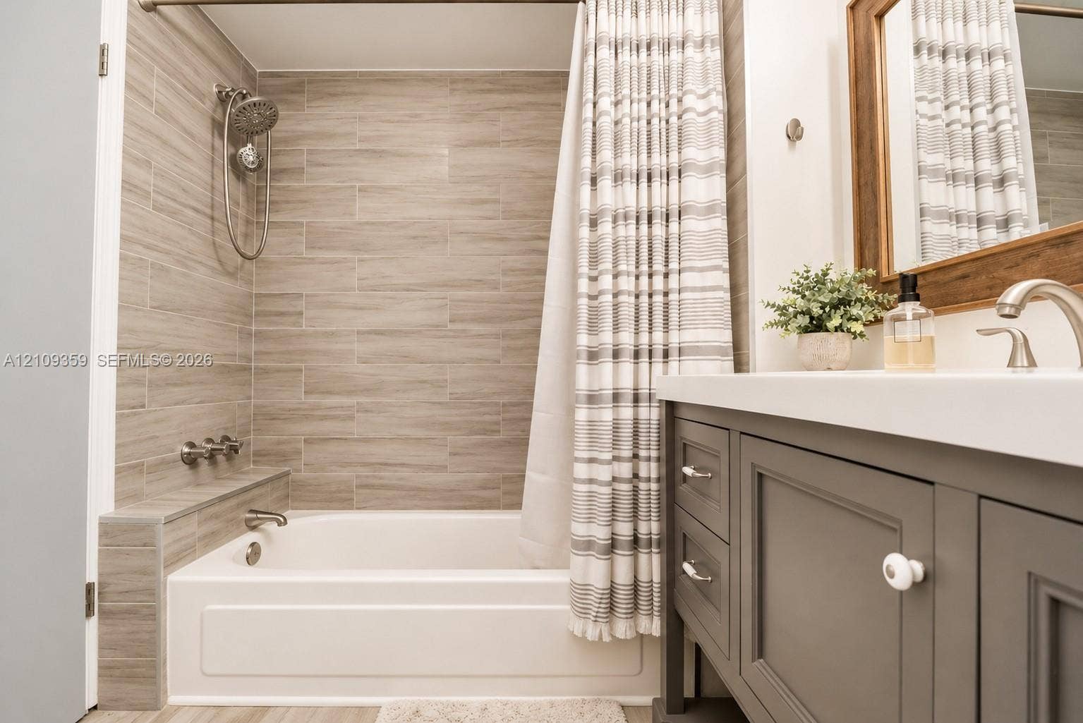 2426 SE 17th Causeway, #103A, Fort Lauderdale, FL 33316 Bathroom featuring a built-in tub with neutral tile surround, multi-function shower head, matte finish vanity, and integrated solid surface countertop with a curved faucet