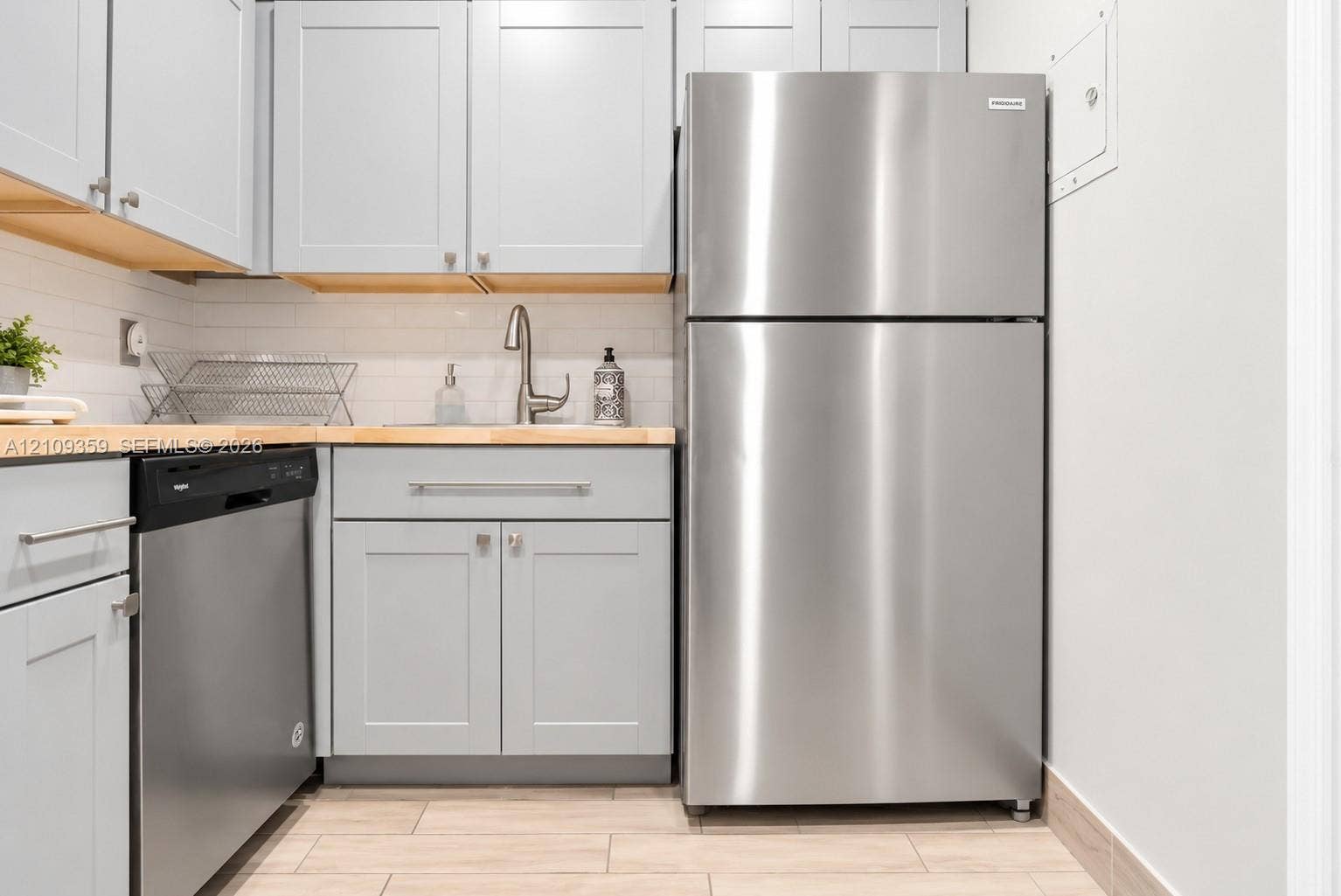 2426 SE 17th Causeway, #103A, Fort Lauderdale, FL 33316 Kitchen featuring shaker-style grey cabinetry, wood-tone countertops, stainless steel appliances, a white subway tile backsplash, and ceramic tile flooring