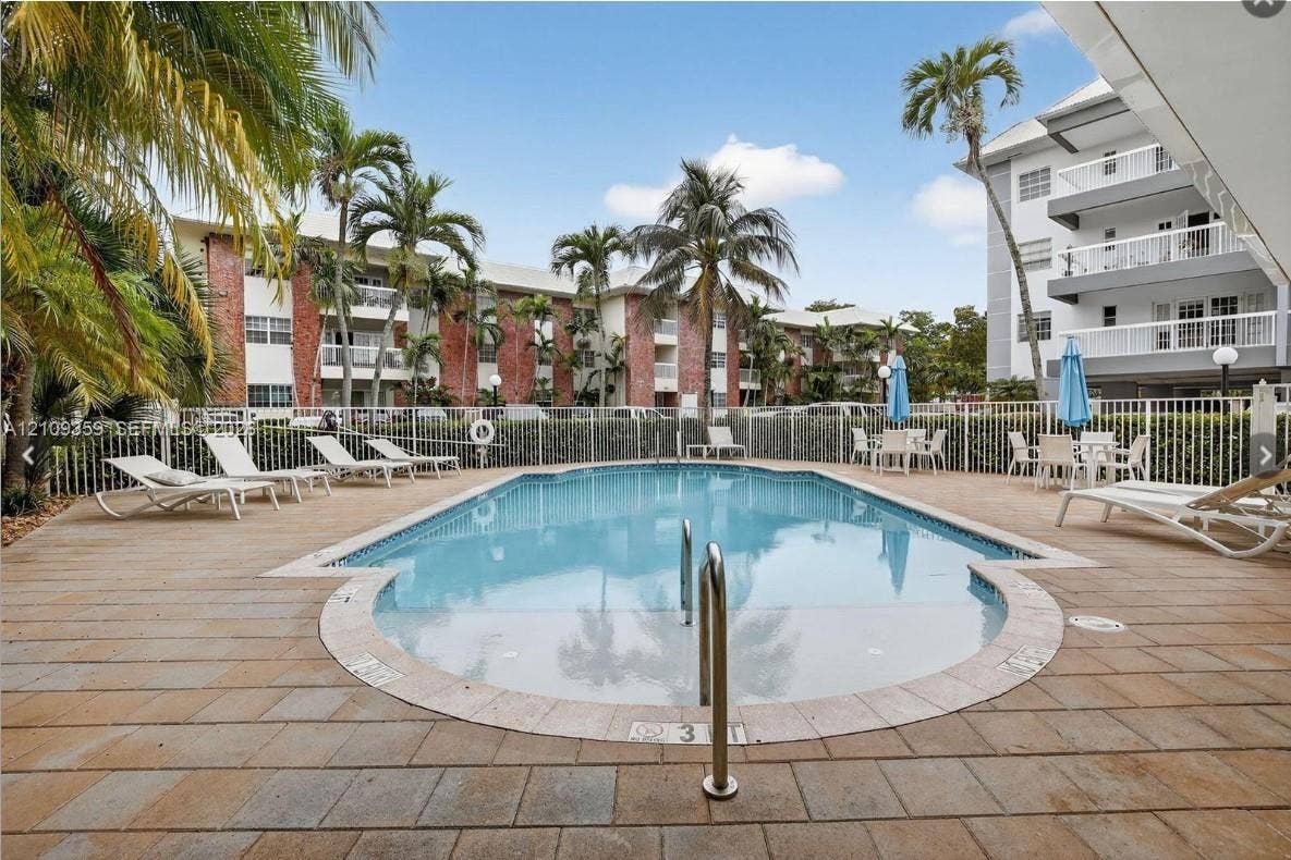 2426 SE 17th Causeway, #103A, Fort Lauderdale, FL 33316 In-ground pool featuring a tiled deck, perimeter fencing, and mature palm trees