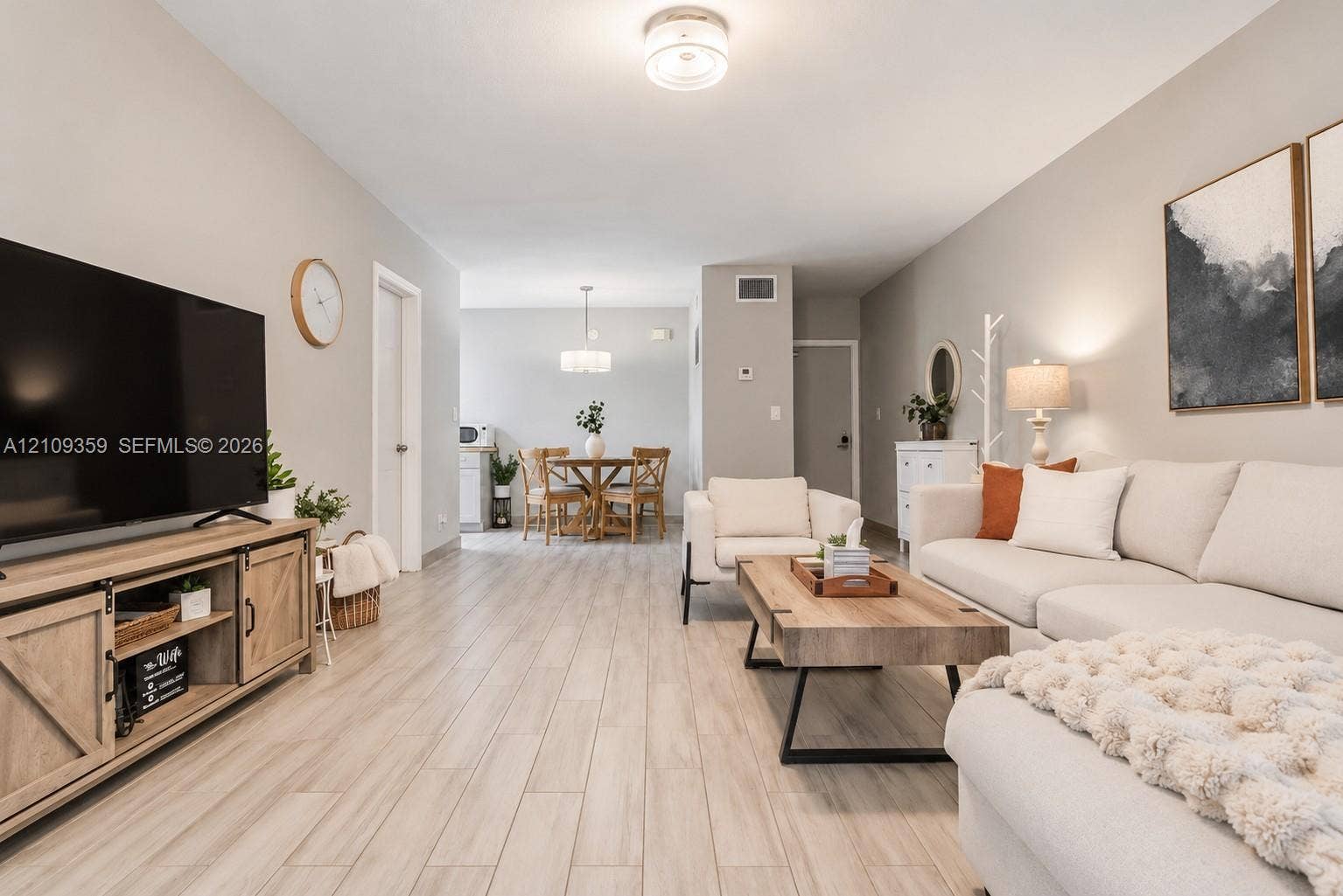 2426 SE 17th Causeway, #103A, Fort Lauderdale, FL 33316 Open-concept interior featuring light wood-finish flooring, neutral wall paint, a circular brushed-nickel dining area chandelier, and a flush-mount overhead light fixture