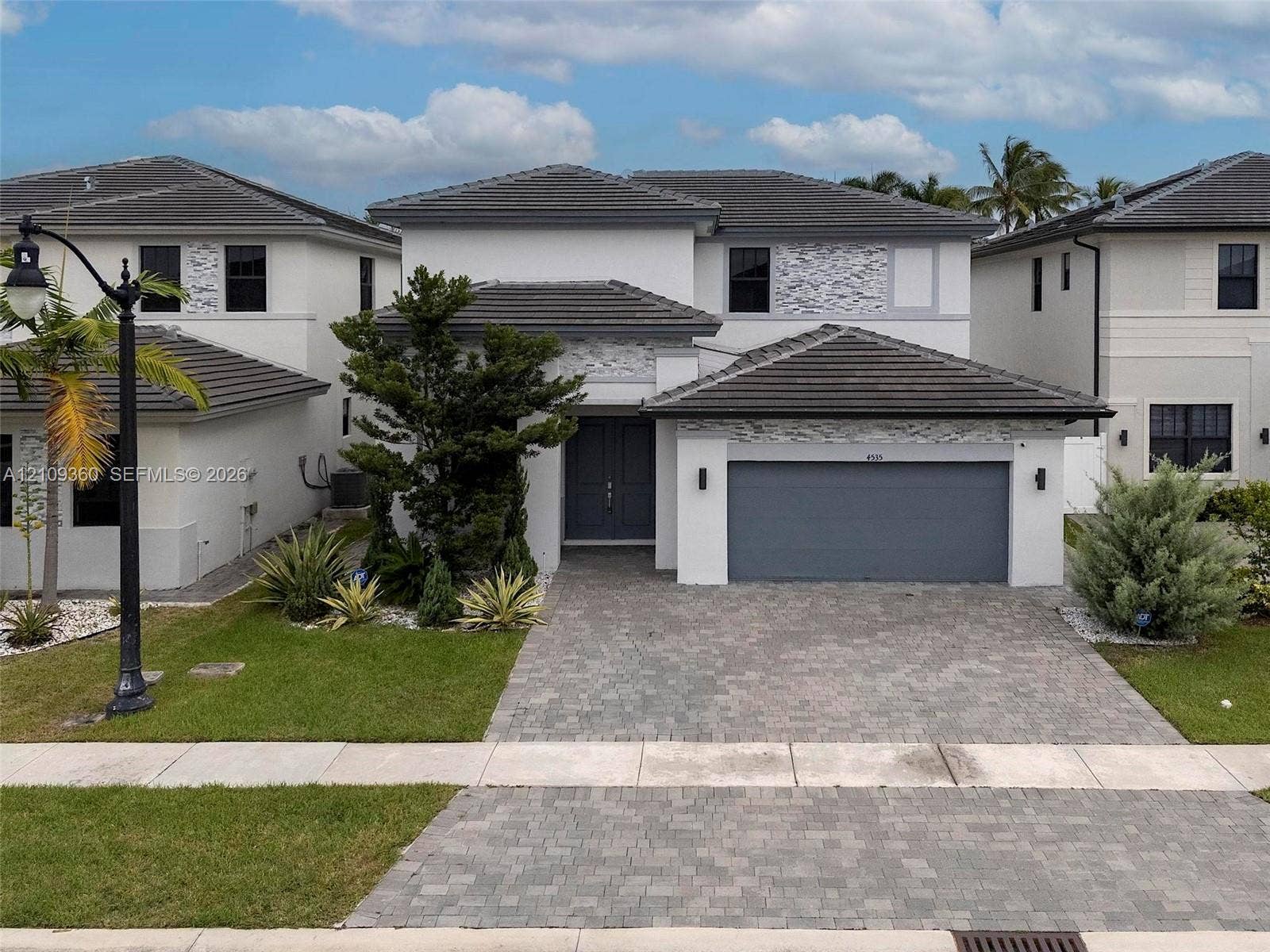 4535 SW 173rd Avenue, Miramar, FL 33029 Two-story exterior featuring a tile roof, decorative stone accents, a multi-car garage, and a paved stone driveway