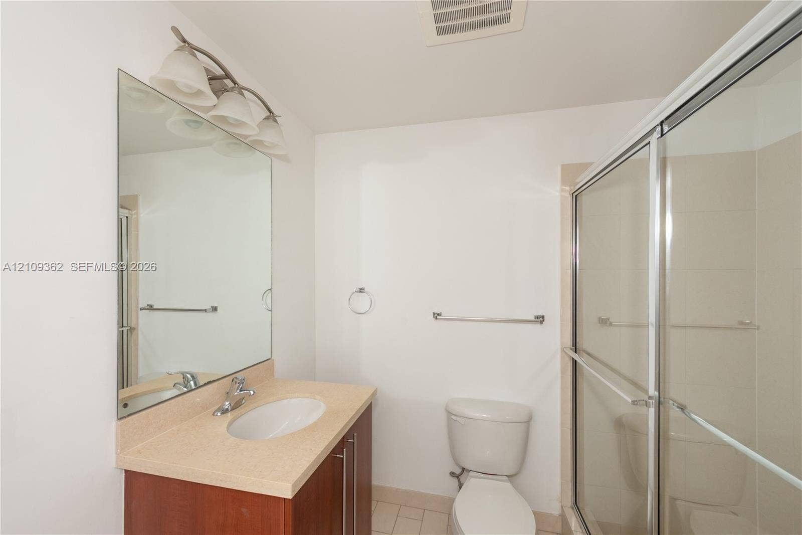 79 SW 12th Street, #1107-S, Miami, FL 33130 Bathroom featuring a single-sink vanity with a solid-surface countertop, full-height wall mirror, multi-bulb light fixture, and a glass-enclosed shower stall