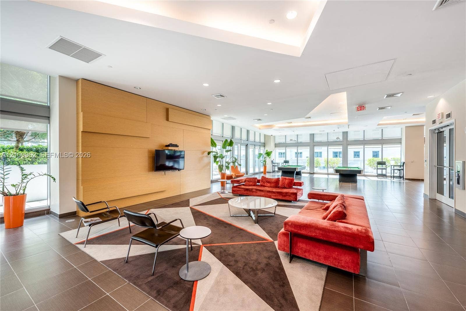79 SW 12th Street, #1107-S, Miami, FL 33130 Spacious common area featuring large-format tile flooring, recessed ceiling lighting, tray ceiling details, floor-to-ceiling windows, and wood-paneled accent wall