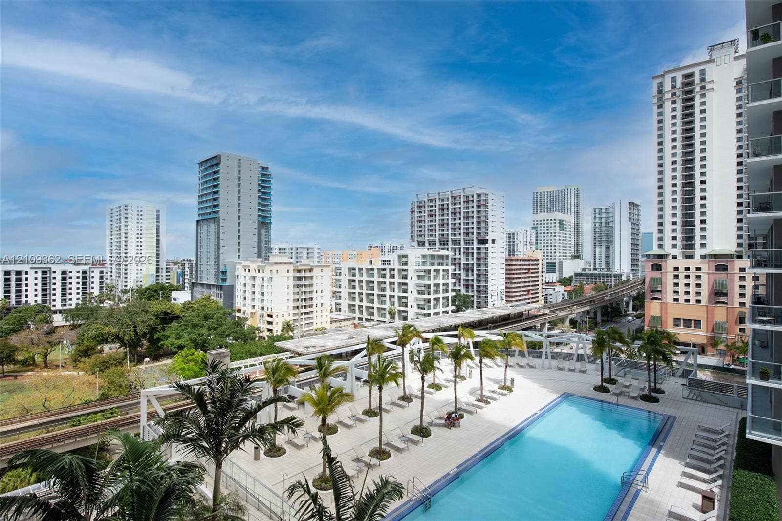 79 SW 12th Street, #1107-S, Miami, FL 33130 Outdoor swimming pool featuring a paved deck, glass railing enclosure, and mature palm tree landscaping