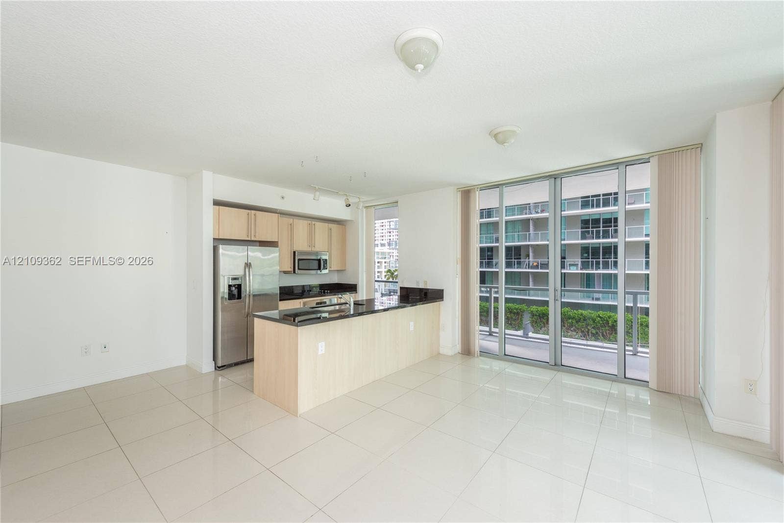 79 SW 12th Street, #1107-S, Miami, FL 33130 Kitchen featuring light-finish cabinetry, dark stone countertops, stainless steel appliances, tile flooring, and floor-to-ceiling glass sliding doors