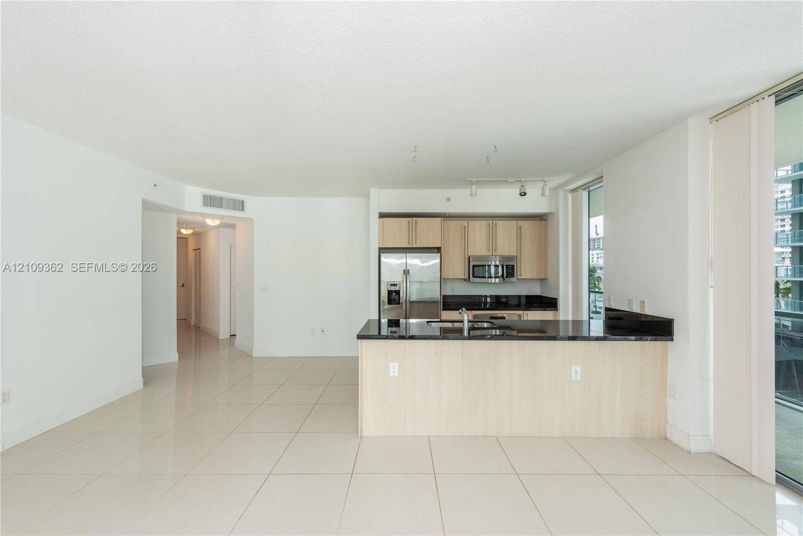 79 SW 12th Street, #1107-S, Miami, FL 33130 Kitchen featuring light-finish cabinetry, dark stone countertops, stainless steel appliances, a peninsula with an integrated sink, and large-format tile flooring