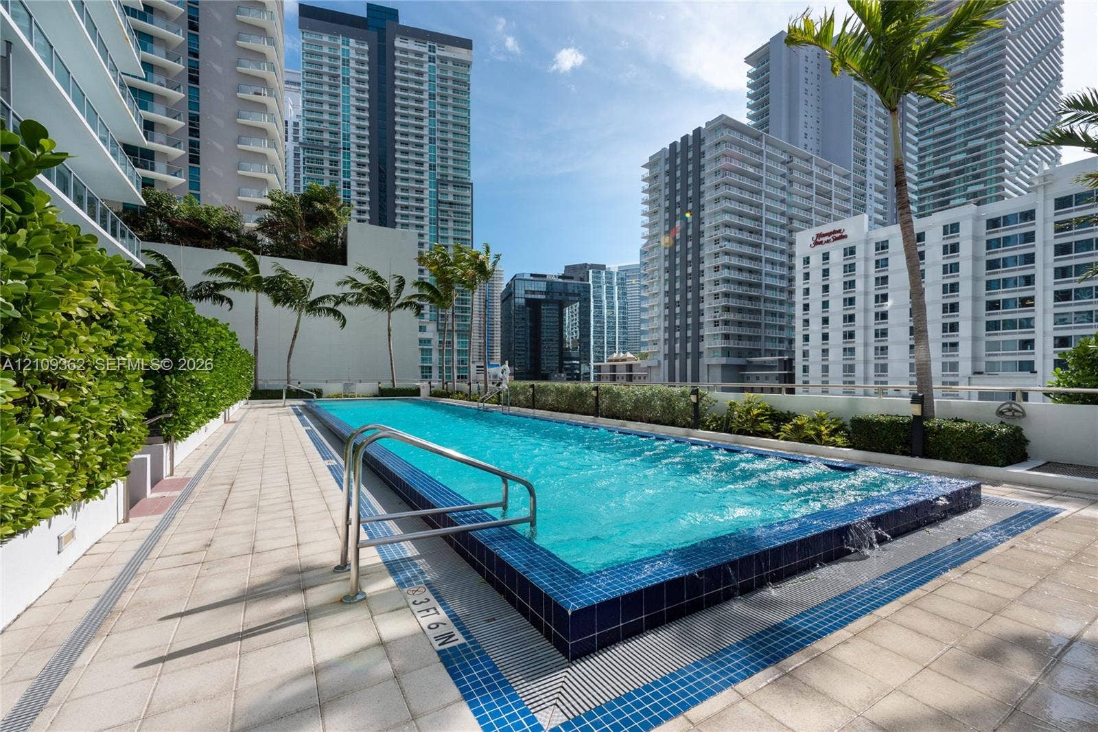 79 SW 12th Street, #1107-S, Miami, FL 33130 Elevated swimming pool featuring a tiled infinity edge, stainless steel grab rails, and surrounding ceramic tile decking