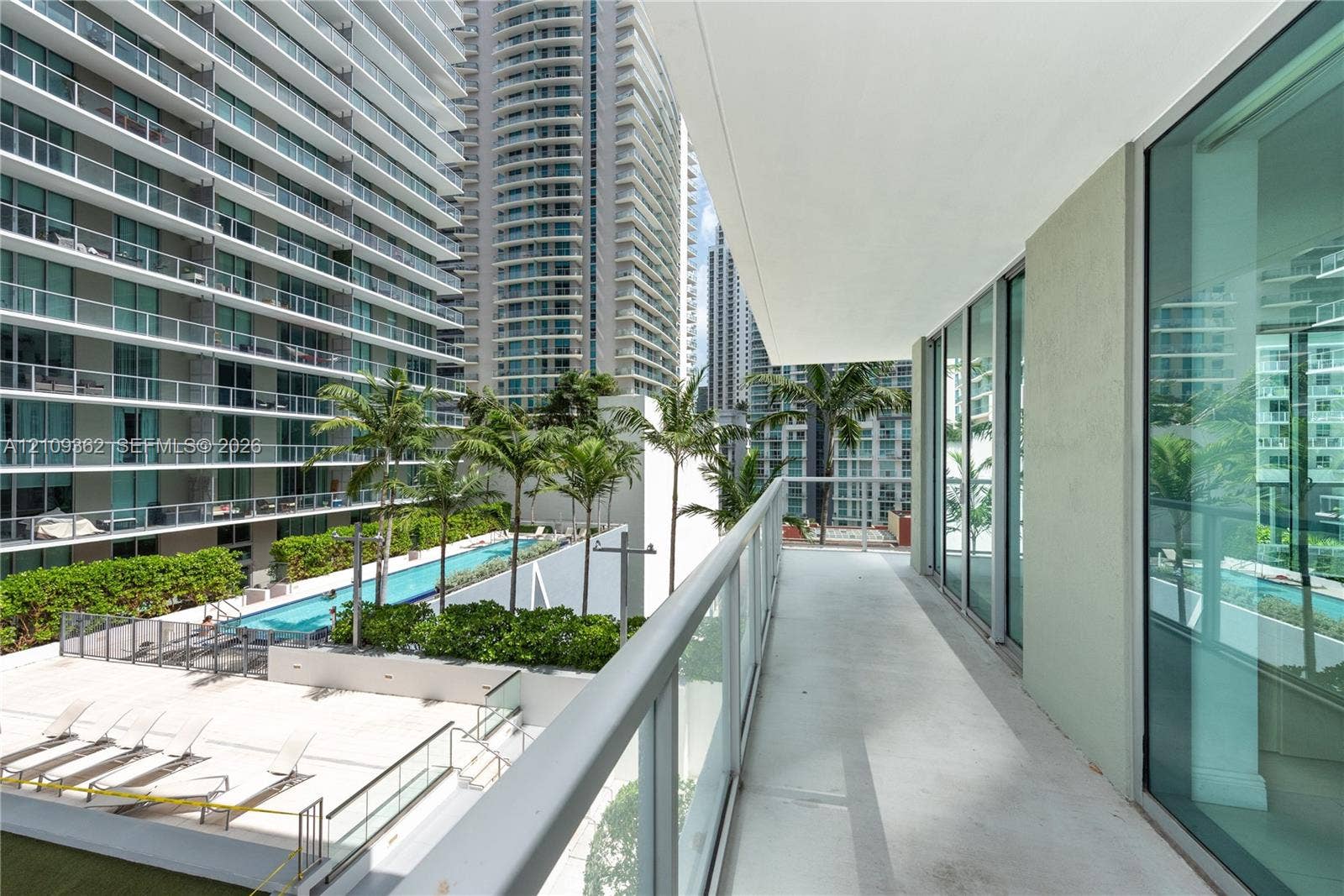 79 SW 12th Street, #1107-S, Miami, FL 33130 Covered balcony featuring a glass-panel railing, concrete flooring, and floor-to-ceiling glass wall