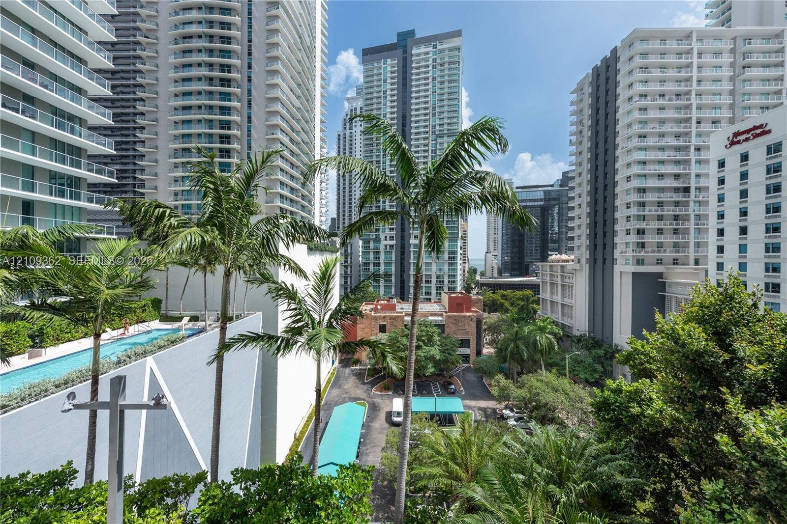 79 SW 12th Street, #1107-S, Miami, FL 33130 Elevated urban perspective featuring high-rise architecture, a rooftop lap pool, palm trees, and paved grounds