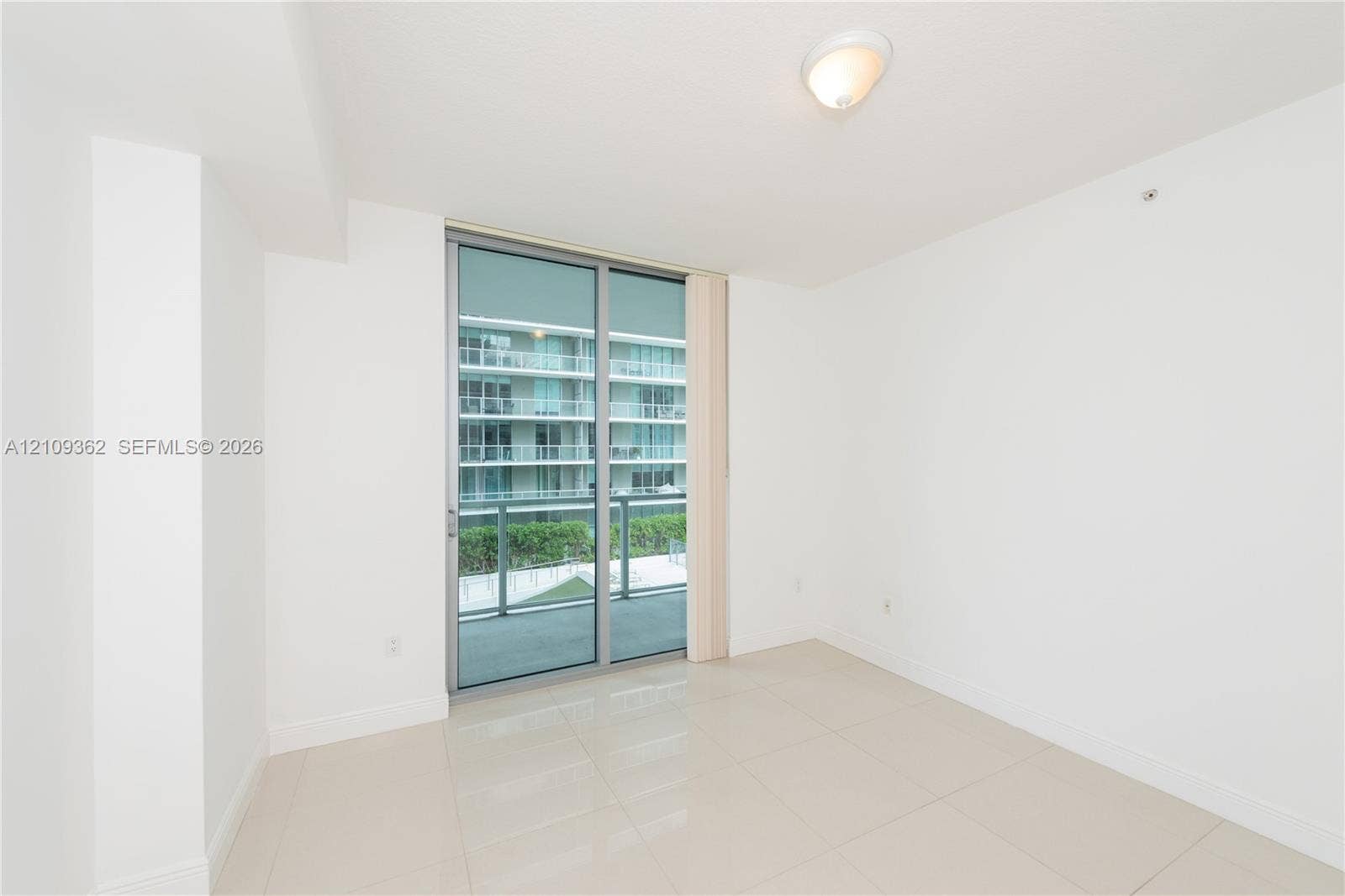 79 SW 12th Street, #1107-S, Miami, FL 33130 Interior space featuring large-format tile flooring, neutral walls, flush-mount ceiling lighting, and sliding glass doors with metallic framing