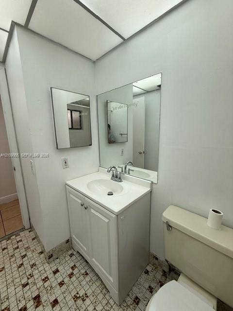 Bathroom vanity featuring a white cabinet base, integrated sink, and dual-handle chrome faucet, complemented by a large wall-mounted mirror and patterned tile flooring