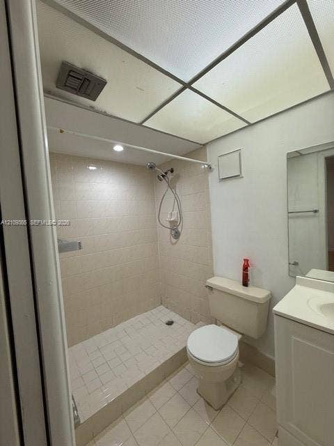 Bathroom featuring a walk-in shower with tile surround, drop-in sink, vanity cabinet, and recessed ceiling panel lighting