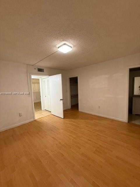 Room featuring wood-finish flooring, a flush-mount ceiling light, and interior access to a walk-in closet