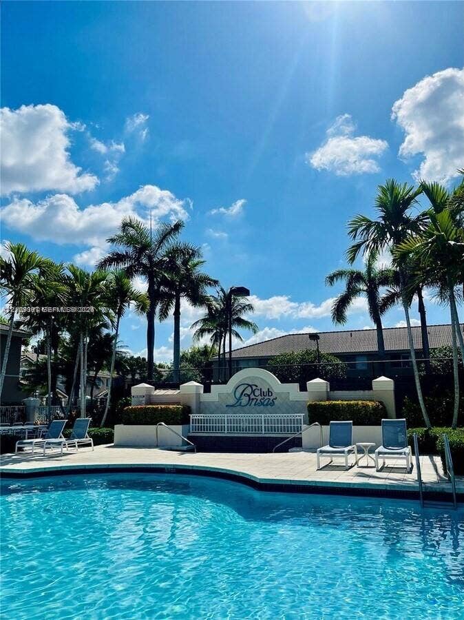 Swimming pool with light-toned deck surfacing and surrounding palm tree landscaping