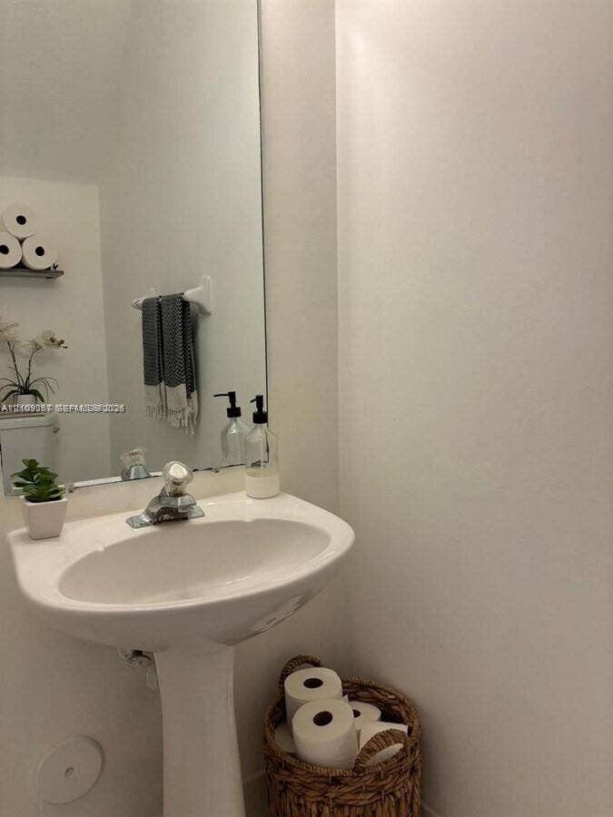 White pedestal sink with a chrome finish faucet and a floor-to-ceiling mirror