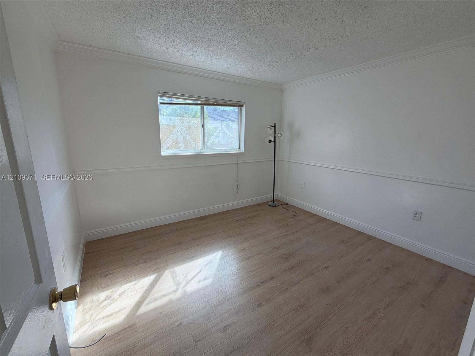 Room featuring wood-finish flooring, chair rail molding, and a single-pane window