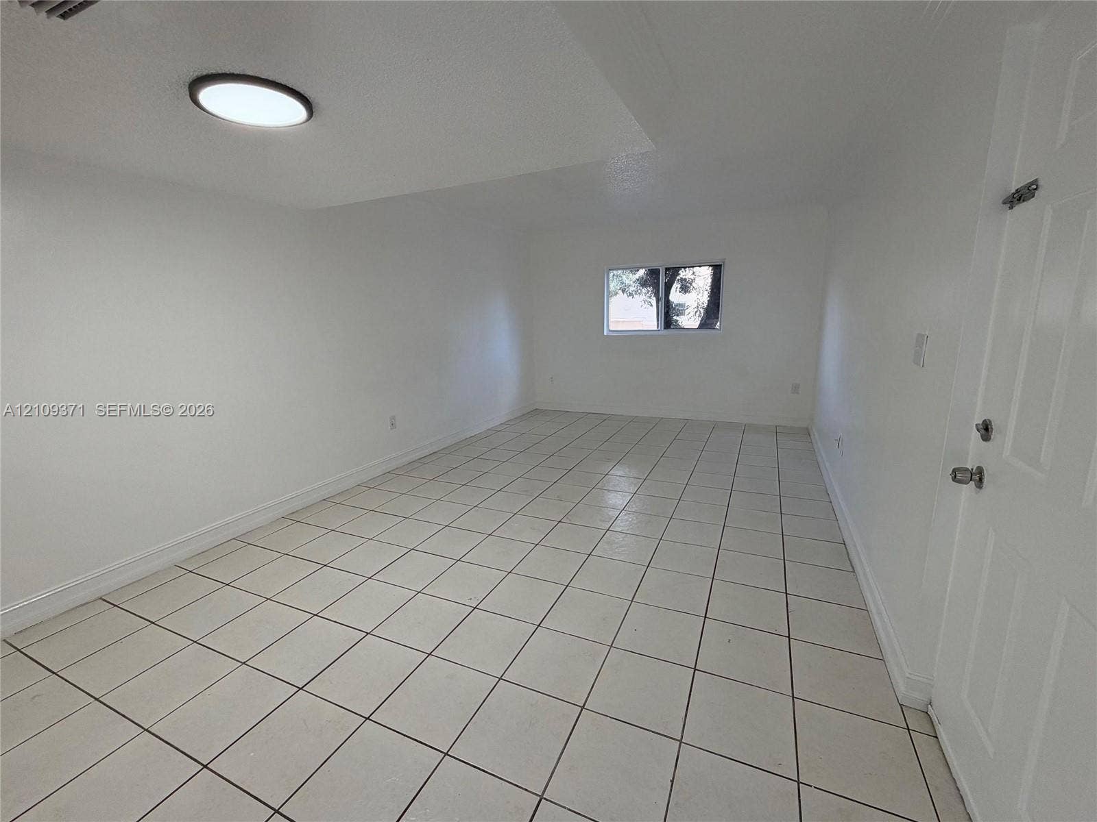 Interior space featuring neutral wall paint, white tile flooring, a recessed ceiling light, and a window