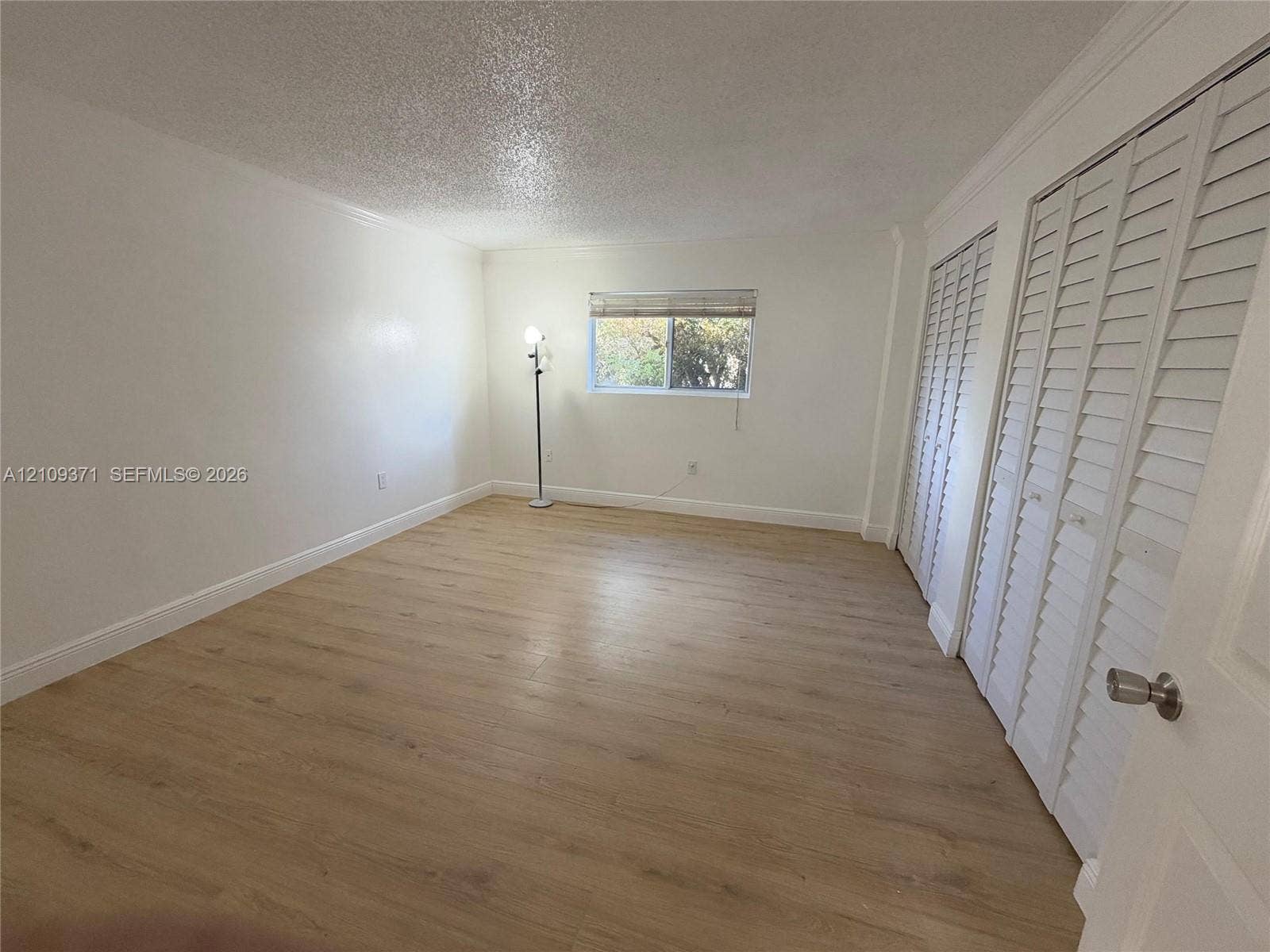 Room featuring wood-finish flooring, white walls, and two sets of louvered bi-fold closet doors