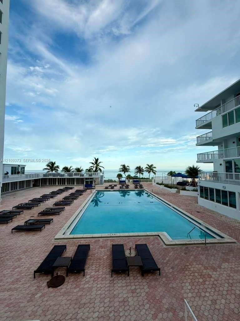 Rectangular swimming pool featuring a concrete deck, multi-level balconies, and water horizon backdrop