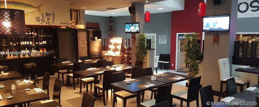 Commercial space featuring a dedicated bar area with built-in bottle shelving, recessed ceiling lighting, decorative pendant lighting, and multi-tone interior wall paint