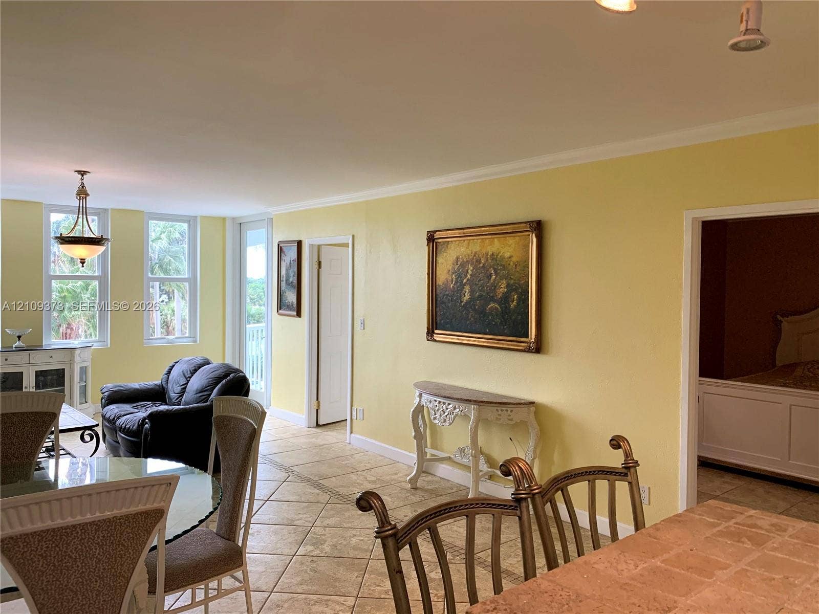 Open living space featuring tile flooring, multi-pane windows, a hanging pendant light fixture, and crown molding