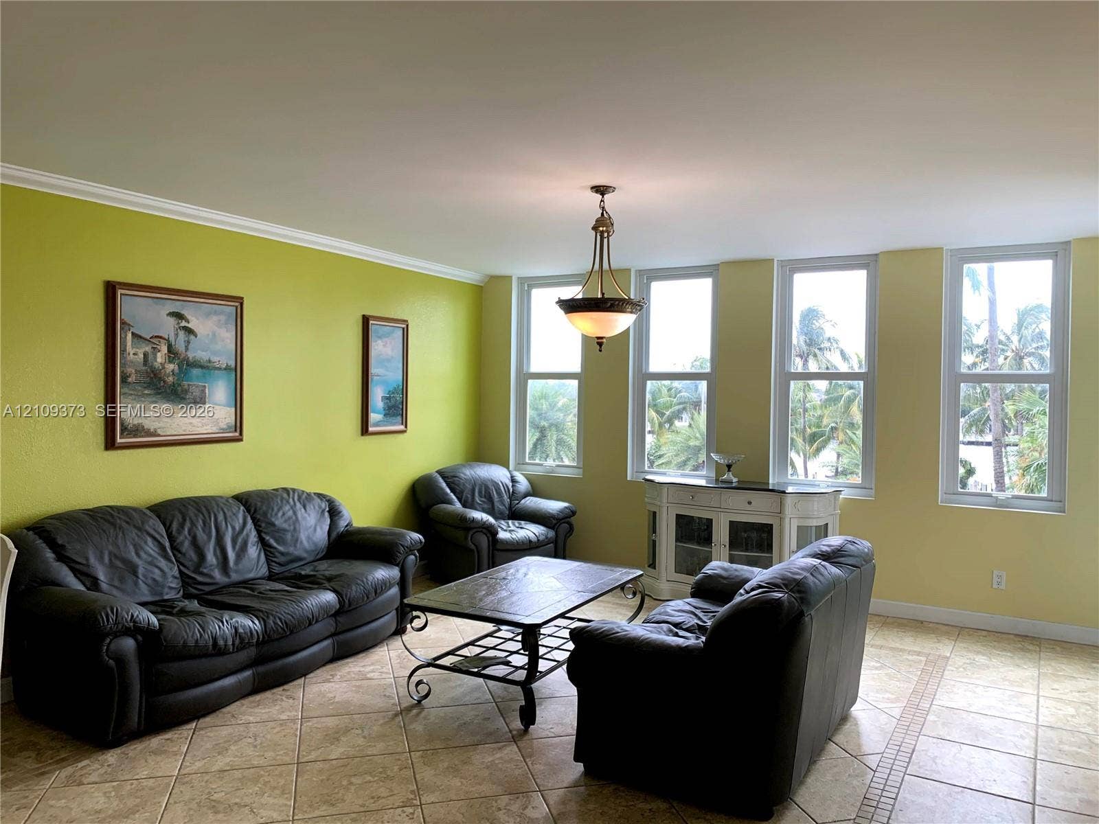 Living area featuring large format diagonal tile flooring, four expansive floor-to-ceiling windows, and a central pendant light fixture