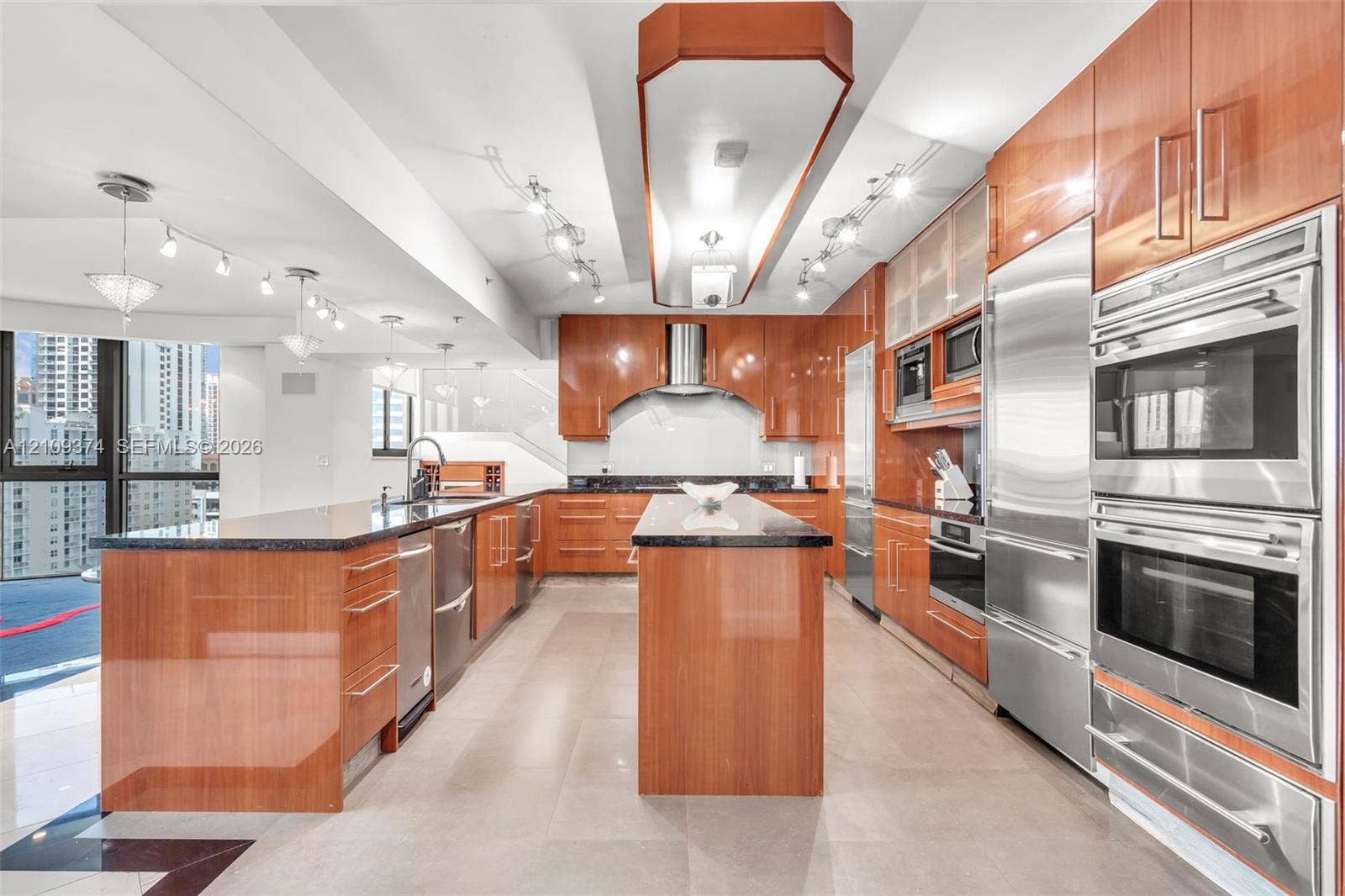 100 N Federal Highway, #1, Fort Lauderdale, FL 33301 Contemporary kitchen featuring high-gloss cabinetry, stone countertops, double wall ovens, integrated stainless steel refrigeration, and a central island with a prep sink