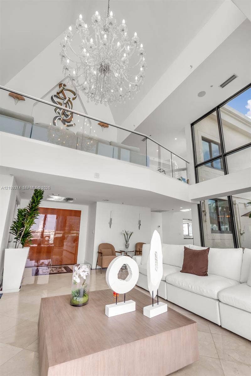 100 N Federal Highway, #1, Fort Lauderdale, FL 33301 Two-story foyer featuring vaulted ceilings, floor-to-ceiling windows, a large multi-tiered crystal chandelier, and a glass-paneled mezzanine railing