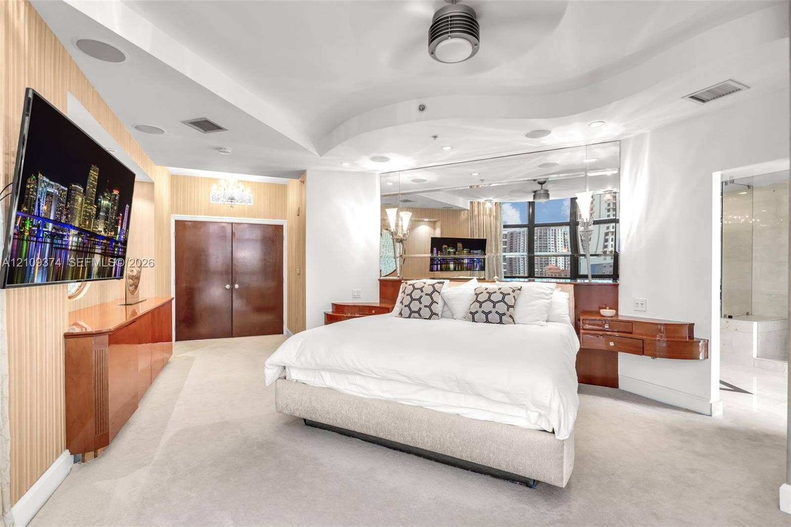 100 N Federal Highway, #1, Fort Lauderdale, FL 33301 Tray ceiling with integrated lighting, mirrored wall accents, built-in mahogany-finish cabinetry, neutral carpeting, and multi-paned windows