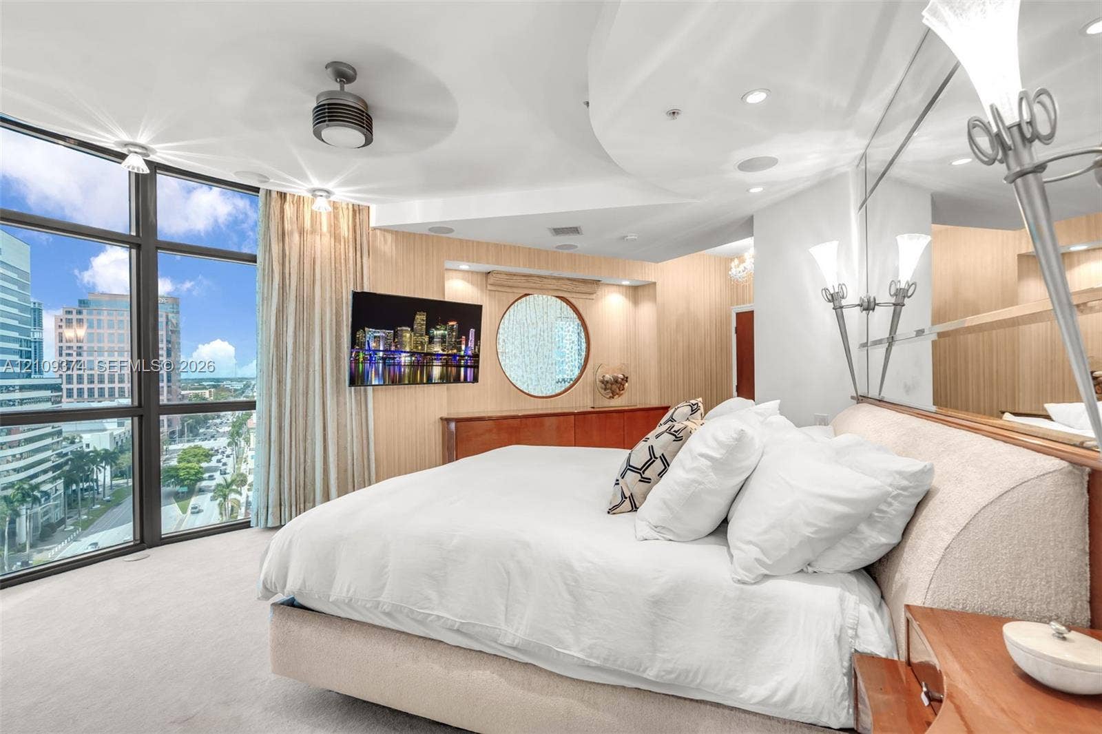 100 N Federal Highway, #1, Fort Lauderdale, FL 33301 Floor-to-ceiling windows with urban scenery, custom wood-paneled wall accents, circular feature window, recessed ceiling lighting, and built-in wall-mounted cabinetry
