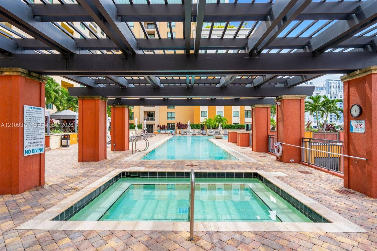 100 N Federal Highway, #1, Fort Lauderdale, FL 33301 Outdoor spa and swimming pool area featuring a large overhead pergola, stone paver decking, and stucco-finished columns