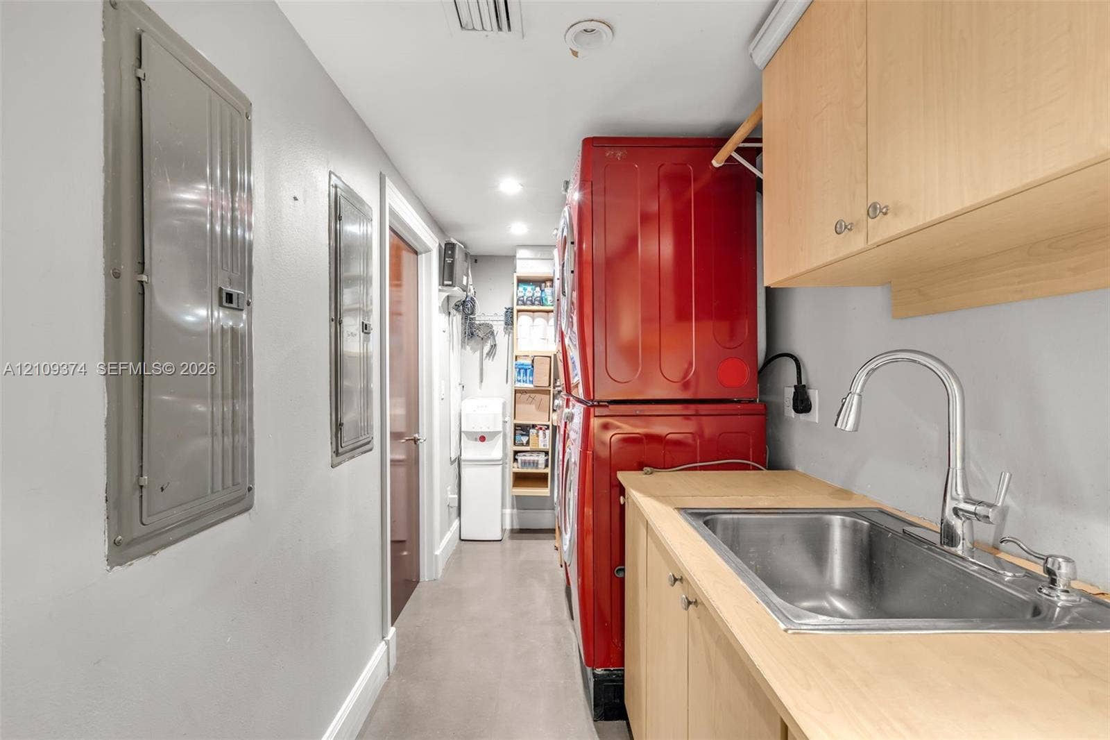 100 N Federal Highway, #1, Fort Lauderdale, FL 33301 Utility room featuring light-finish cabinetry, a stainless steel sink with a high-arch pull-down faucet, and dedicated built-in shelving
