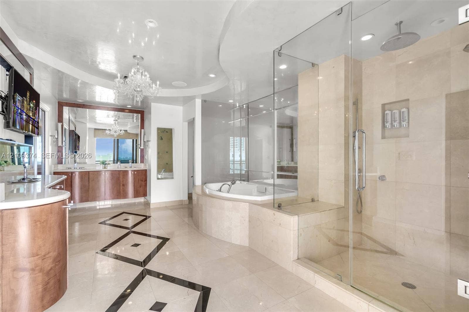 100 N Federal Highway, #1, Fort Lauderdale, FL 33301 Bathroom featuring stone tile flooring with decorative inlay, a glass-enclosed shower with integrated shelving, a built-in soaking tub, wood-finish cabinetry with stone surfaces, and a ceiling-mounted crystal chandelier
