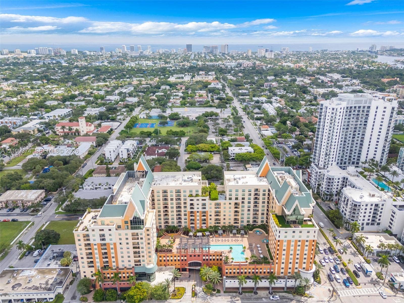 100 N Federal Highway, #1, Fort Lauderdale, FL 33301 Aerial perspective of a multi-story residential complex featuring a central outdoor swimming pool, terracotta-toned facade, decorative pitched roofing, and expansive terrace levels