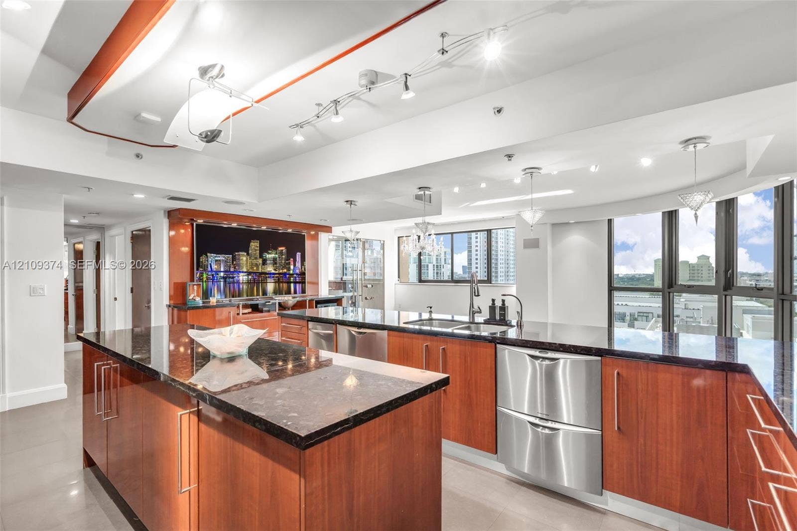 100 N Federal Highway, #1, Fort Lauderdale, FL 33301 Kitchen featuring wood-veneer cabinetry, stone countertops, stainless steel appliances, tiered tray ceiling with recessed lighting, and floor-to-ceiling windows