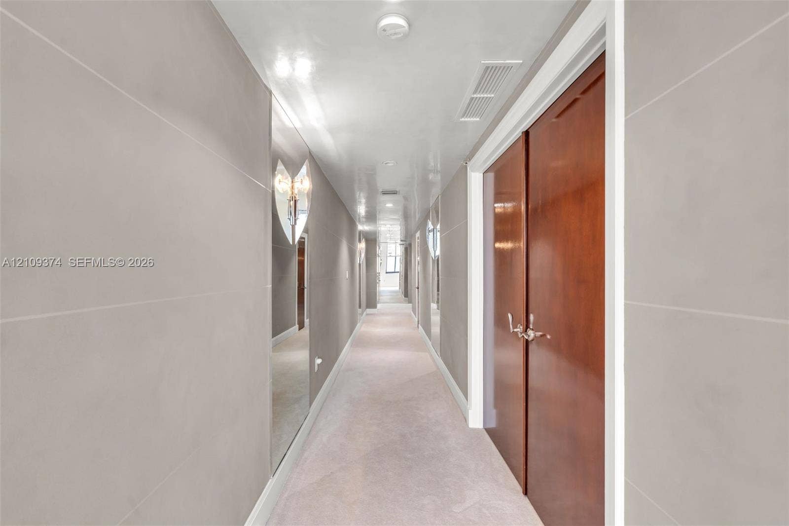 100 N Federal Highway, #1, Fort Lauderdale, FL 33301 Hallway featuring large-format light gray wall panels, full-height wall mirrors, double-door wood cabinetry, and recessed lighting