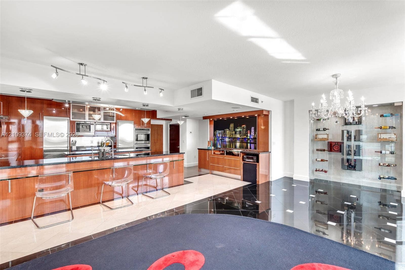 100 N Federal Highway, #1, Fort Lauderdale, FL 33301 Modern kitchen featuring high-gloss cabinetry, dark stone countertops, built-in stainless steel appliances, a recessed wet bar, and a floor-to-ceiling glass-enclosed wine display