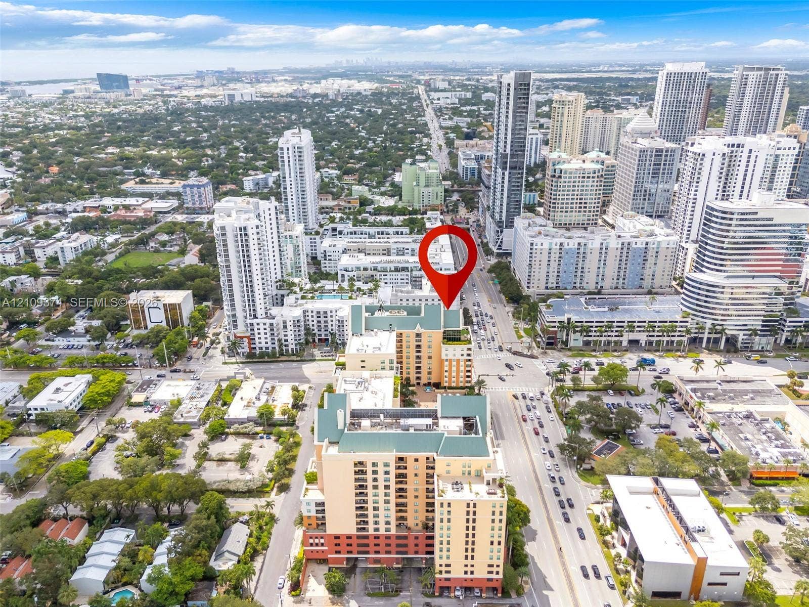 100 N Federal Highway, #1, Fort Lauderdale, FL 33301 Aerial perspective of a multi-story urban complex featuring a tan and brick-toned facade, gabled green roofing, and ground-level perimeter landscaping